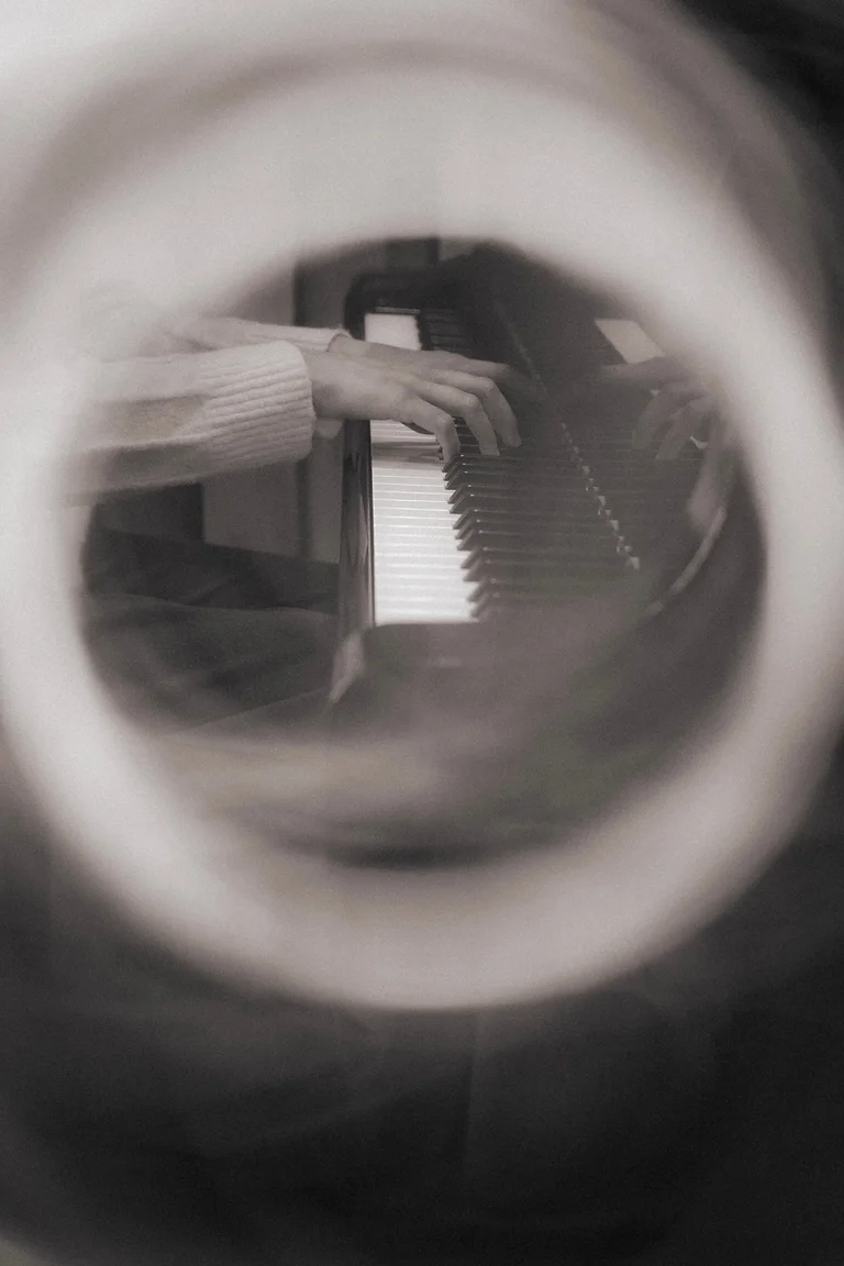 A reflected view of a hand at the piano in a soft monochrome photograph