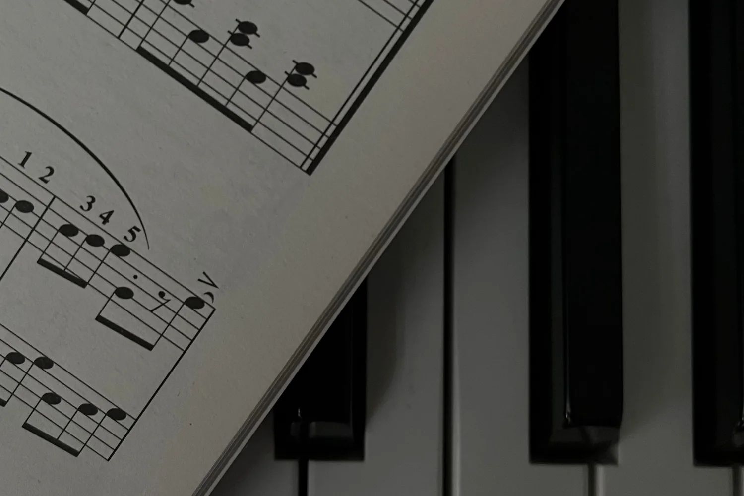 Black-and-white close-up of printed notation lying diagonally across piano keys