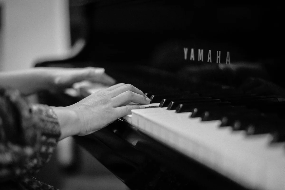 Black-and-white close-up of a pianist’s hands at a grand piano