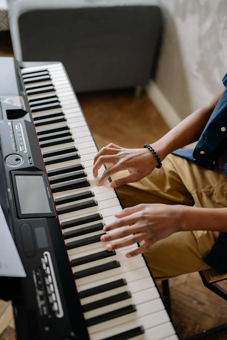 Close-up of two hands playing an electronic keyboard at home