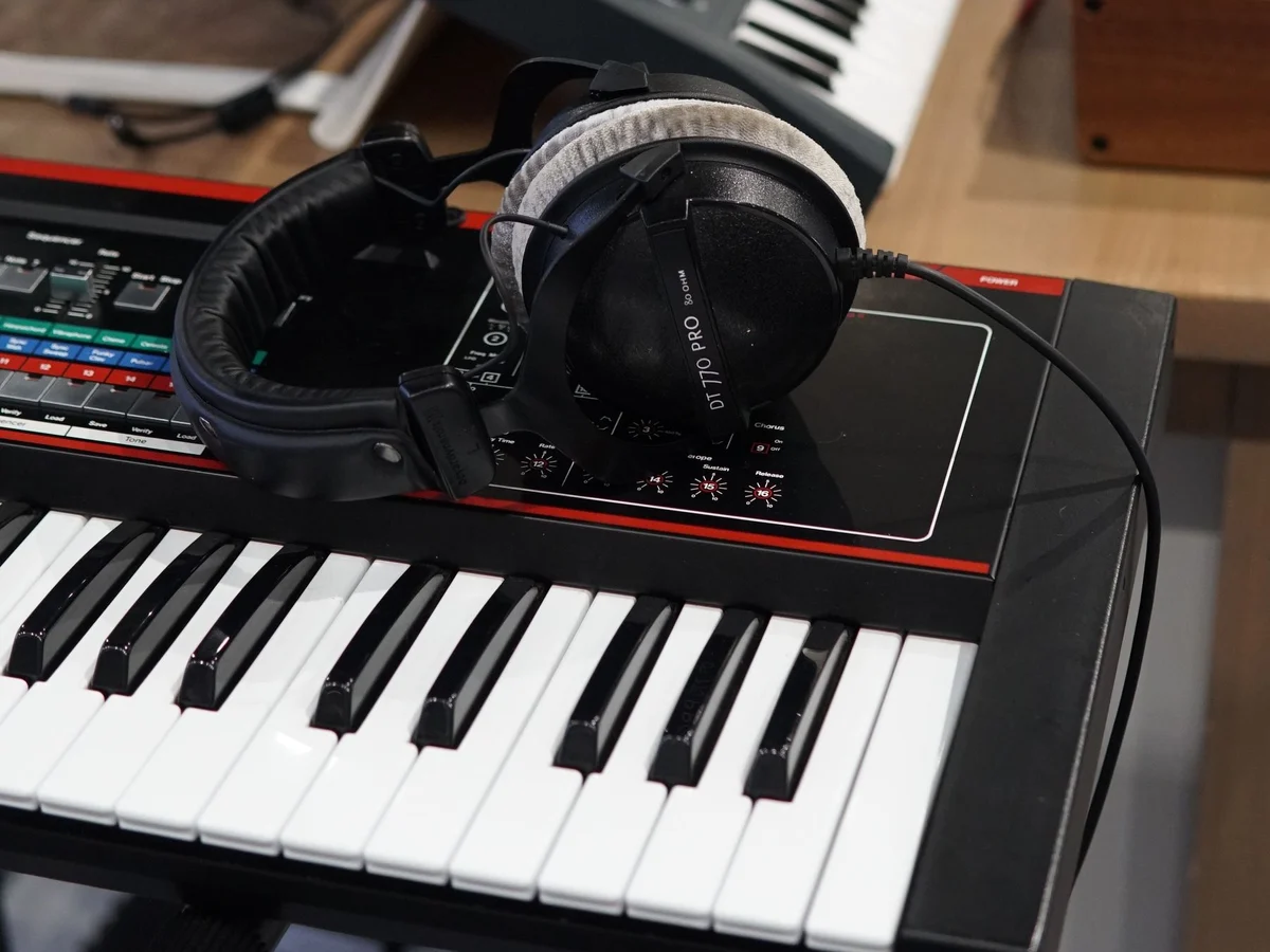 Headphones resting above the keys of an electronic keyboard in a music workspace