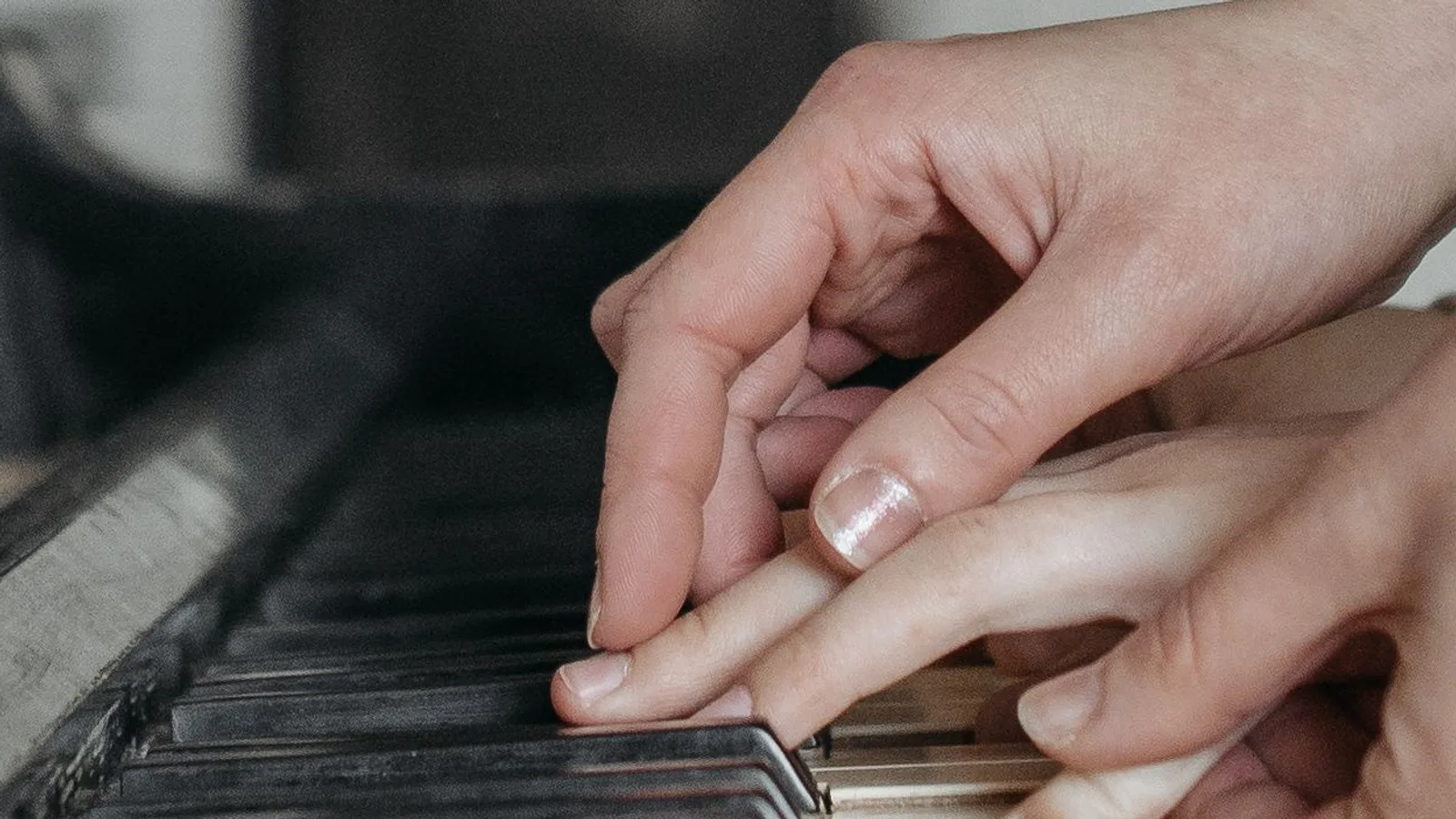 Hands working together over a piano keyboard
