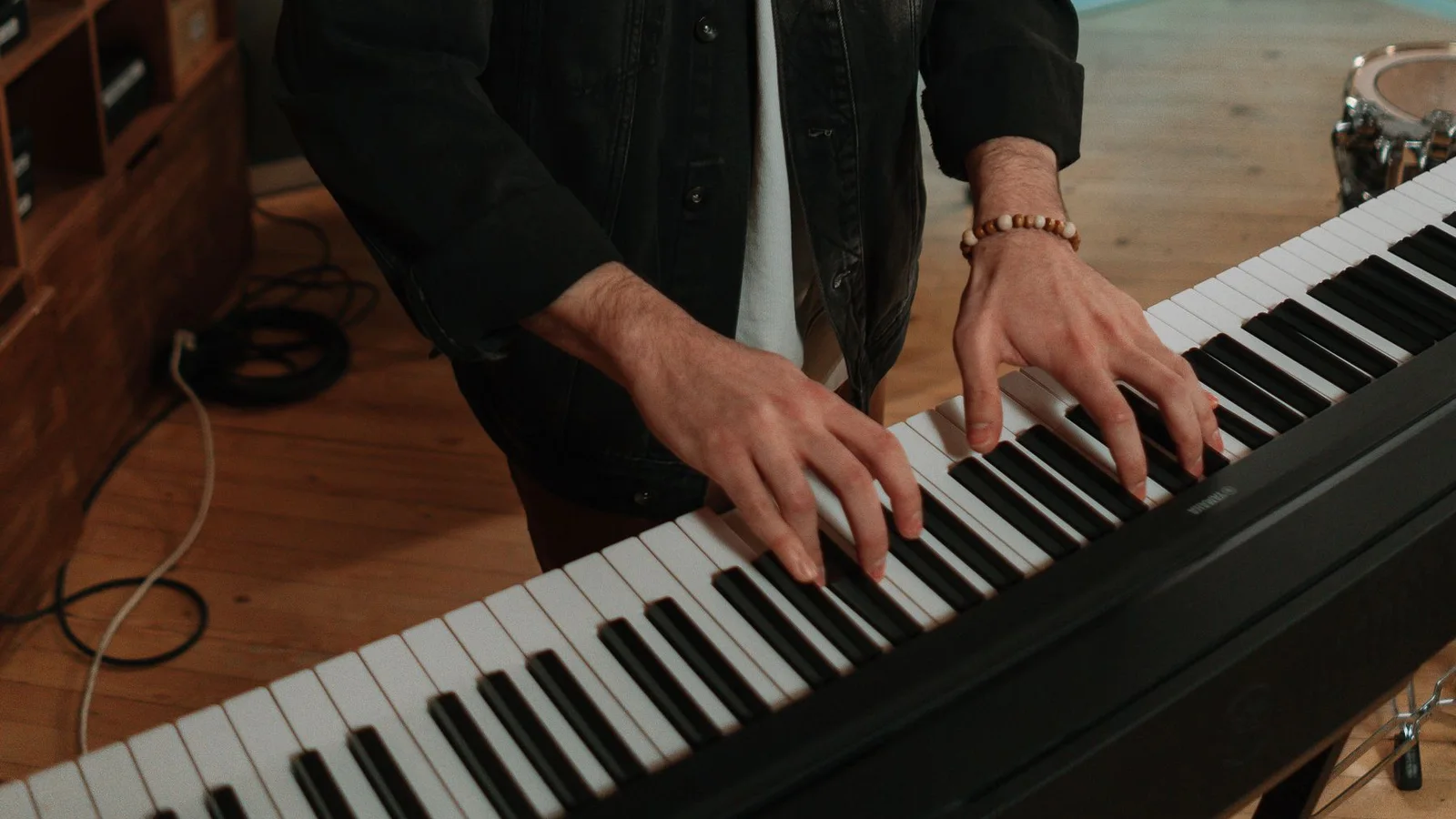 Close-up of a musician’s hands playing an electronic keyboard in a studio
