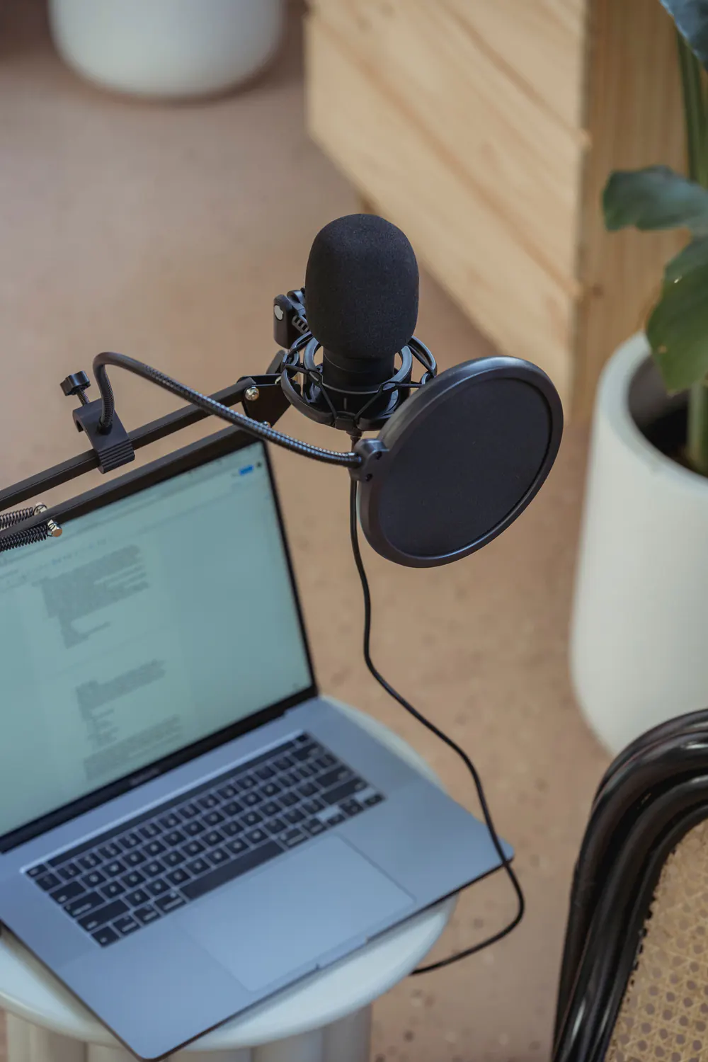 Laptop beside a tripod-mounted microphone and pop filter.