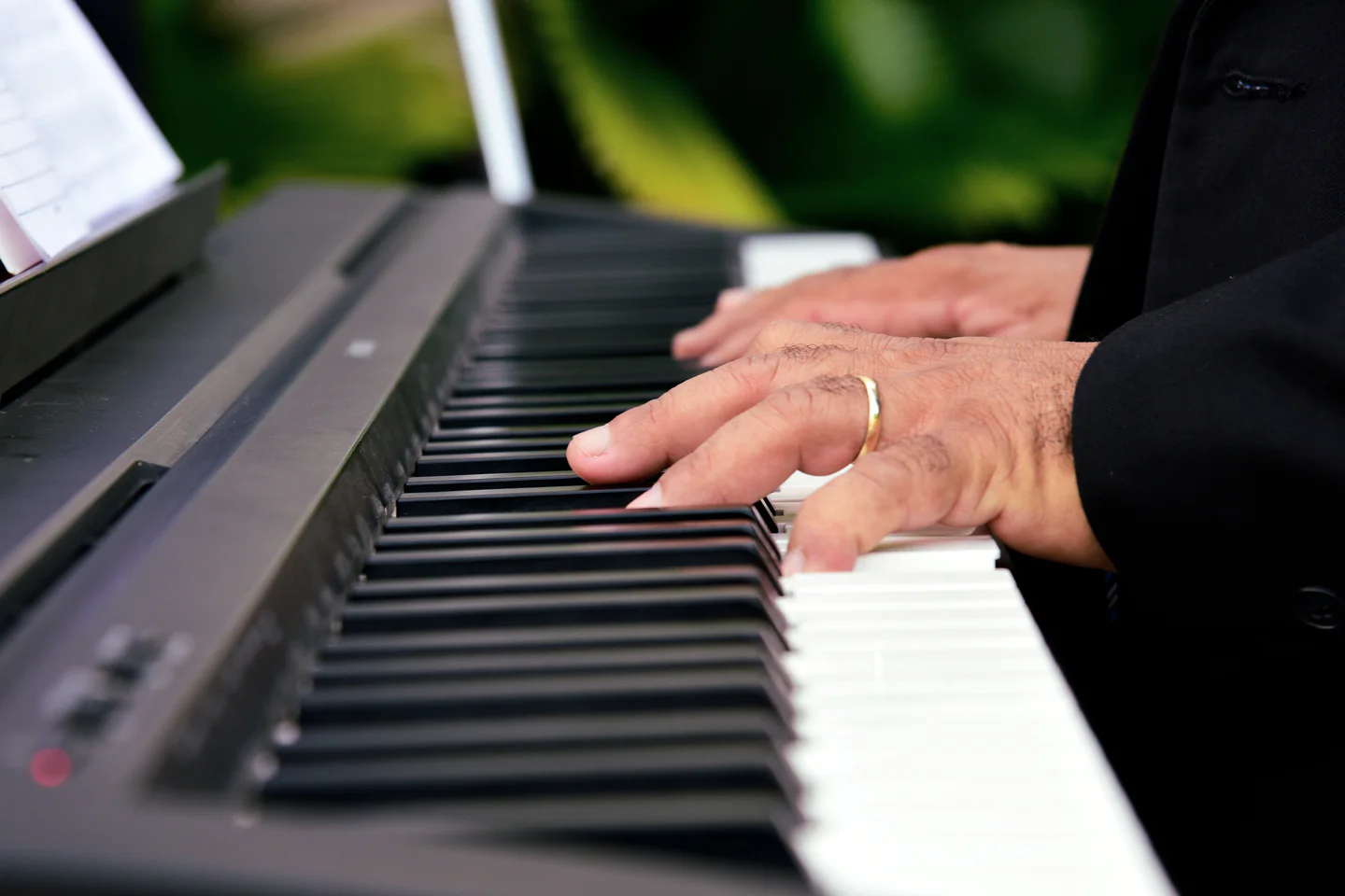 Both hands playing a digital piano keyboard.
