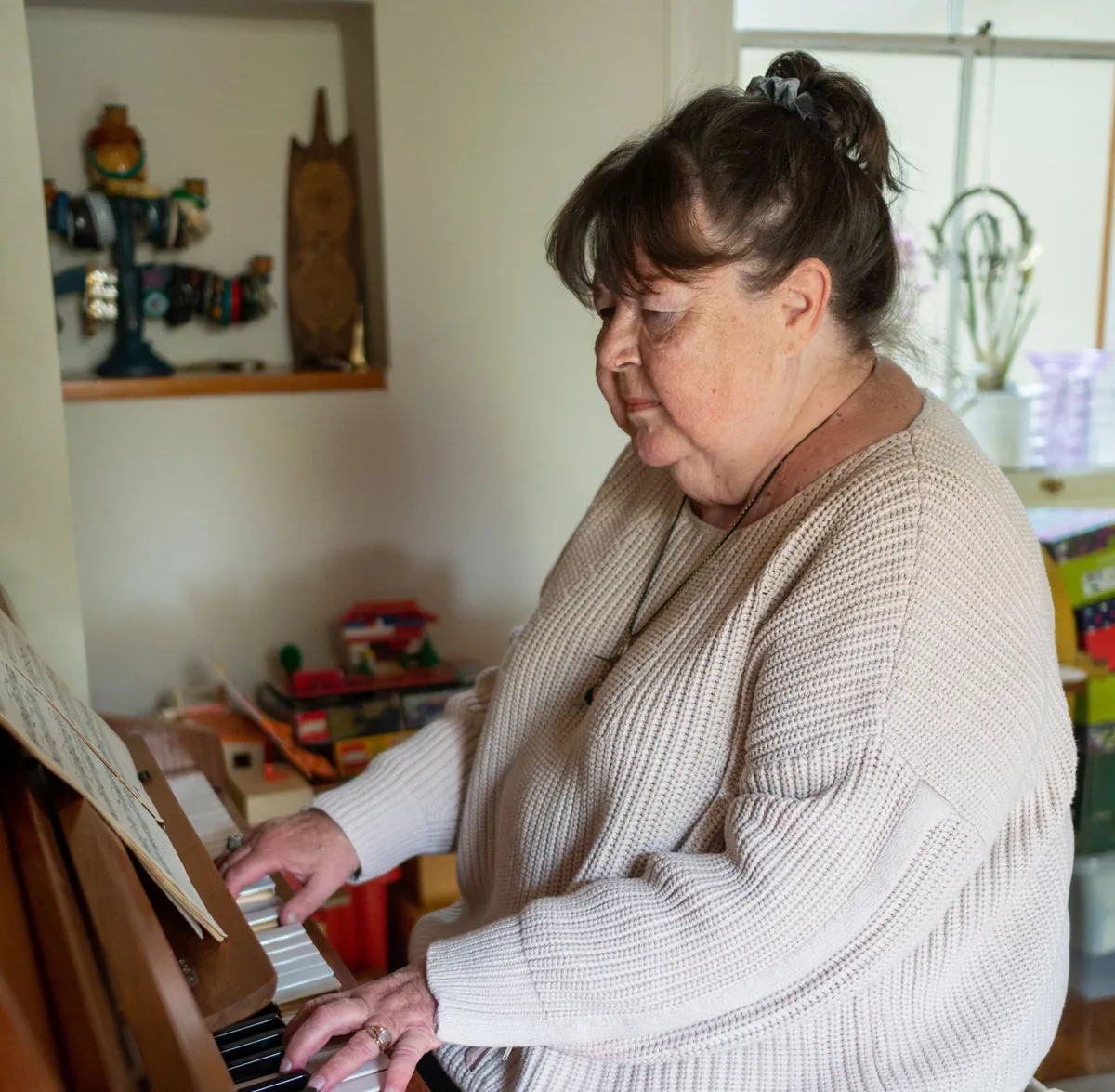 An adult pianist playing a wooden upright piano at home