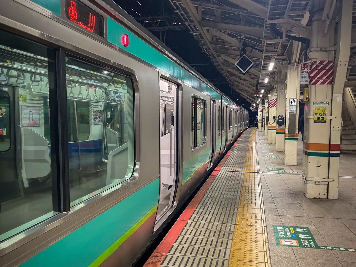 夜の東京の駅で停車する電車と、照明に照らされたホーム。