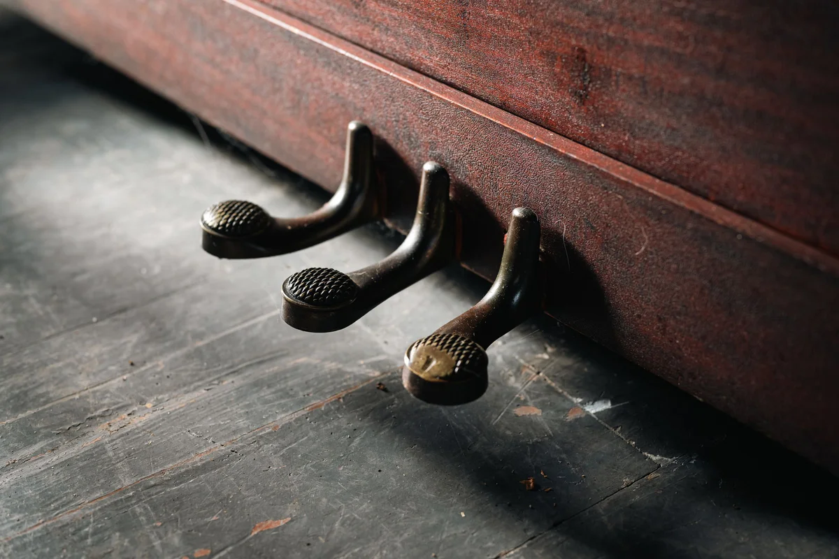 Three piano pedals above a wooden floor